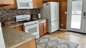 A kitchen with wooden cabinets, a white refrigerator, a microwave, and a stove.