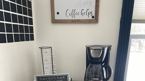 A kitchen area with a coffee maker, a coffee scale, and a sign that reads "haven't had coffee yet."