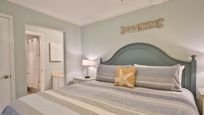 A bedroom with a bed, a nightstand, a lamp, a closet, and a wall sign that reads "Beach House". - Summit 1218, 1 Bedroom, Beachfront Slps 5 w/Beach Chairs! (Panama City Beach)