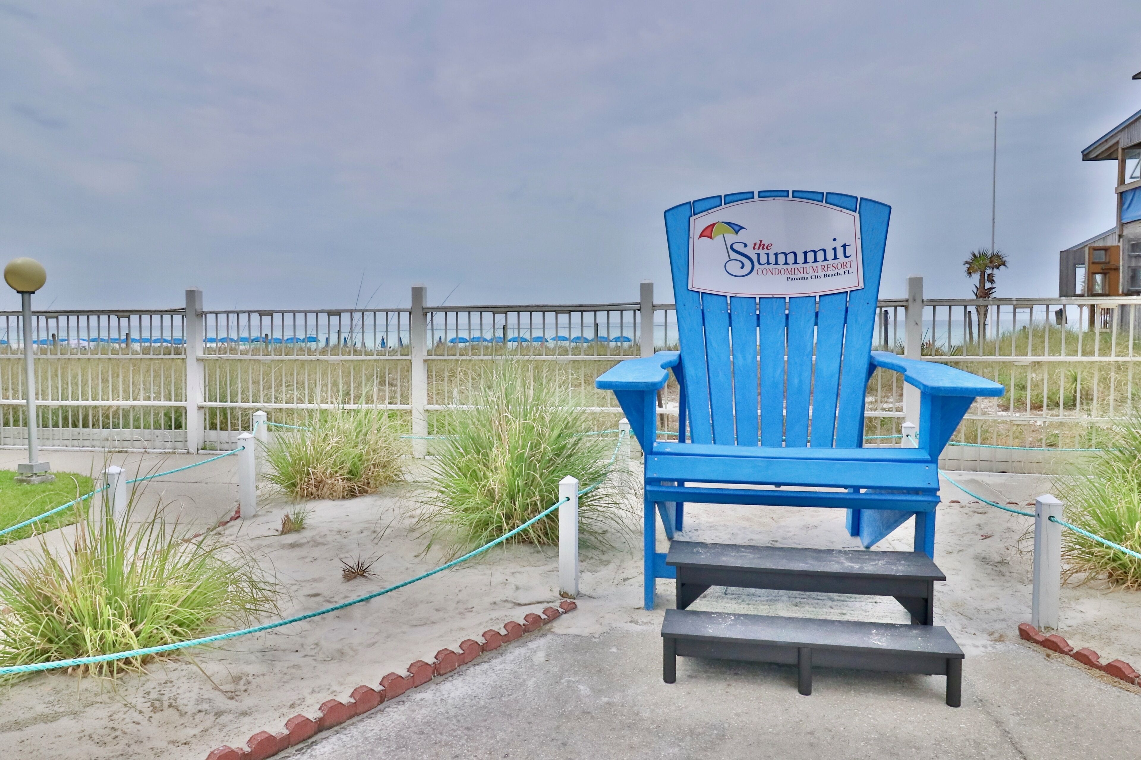 A blue Adirondack chair with a sign reading "The Summit Condominium Resort" in Panama City Beach, FL.