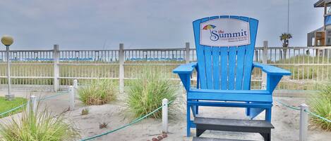 A blue Adirondack chair with a sign reading "The Summit Condominium Resort" in Panama City Beach, FL.