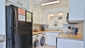 A compact kitchen with a refrigerator, washing machine, and a built-in oven. - Summit 1218, 1 Bedroom, Beachfront Slps 5 w/Beach Chairs! (Panama City Beach)