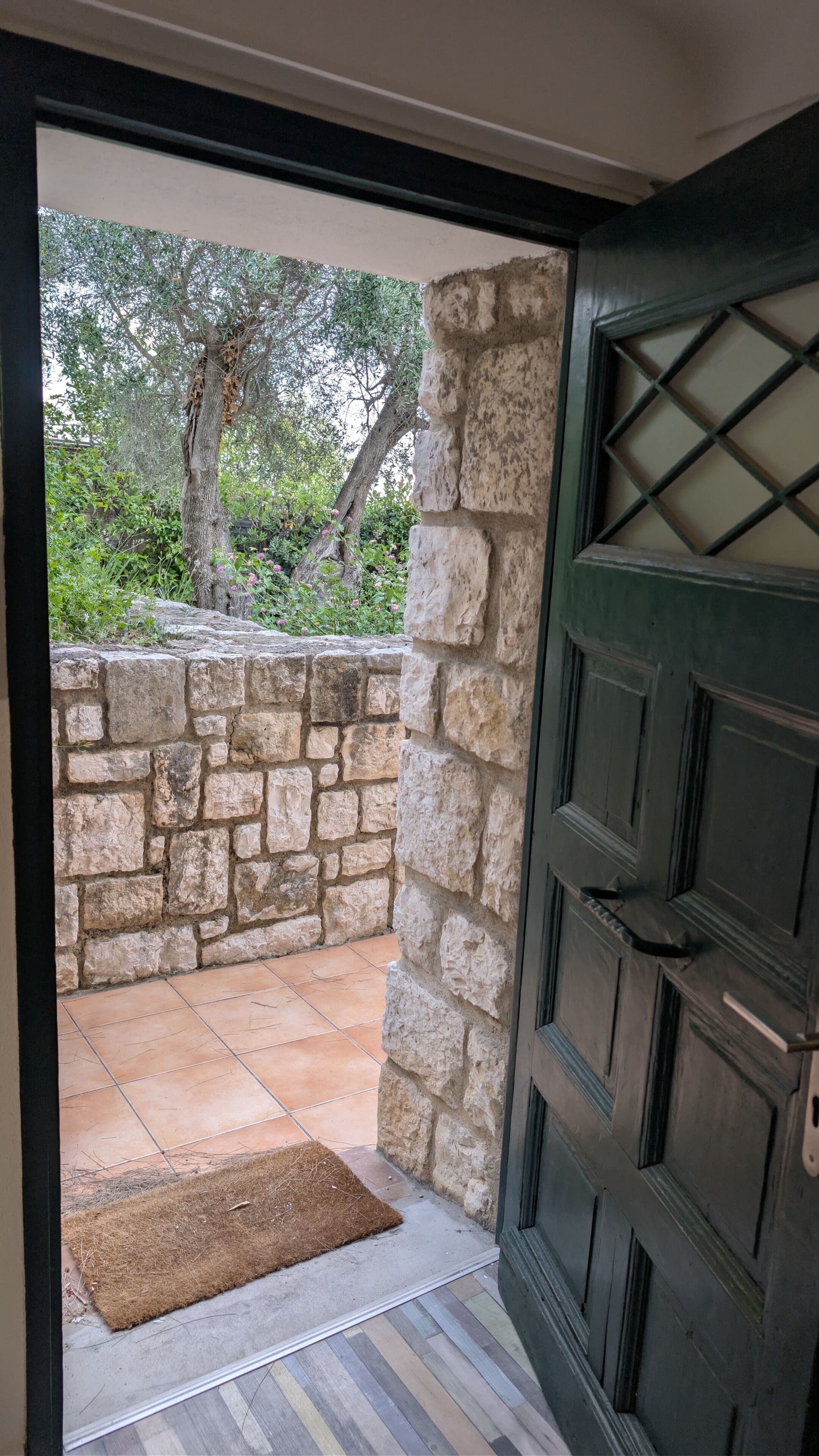 A stone wall, a wooden door, and a tiled patio area.