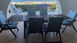 A patio with a table and chairs, a view of the sea, and a hedge in the background. - Adorable cottage with pool and Ocean view (Nice)