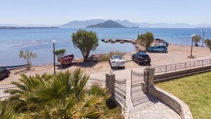 A coastal parking area with vehicles, a boat, and a view of the sea and mountains. - Angela's Guest House (AEGINA)