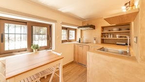 A compact kitchen with wooden cabinets, a sink, and a window. - Angela's Guest House (AEGINA)
