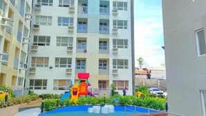 A multi-story residential building with balconies and a playground area in the foreground.