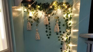 A corner with two black chairs, a wall decorated with hanging lanterns and green vines, and a window on the left.