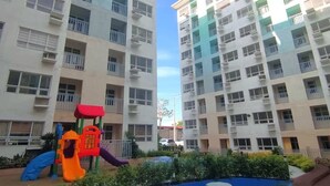A residential building with multiple balconies and a playground area with slides and play structures.