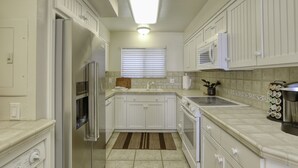 A kitchen with white cabinets, a refrigerator, an oven, a microwave, and a sink. - Classic California Oceanfront Living (Pismo Beach)