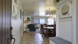 A spacious living area with a dining table, chairs, and a bench. There is a fireplace with a mirror above it. - Classic California Oceanfront Living (Pismo Beach)
