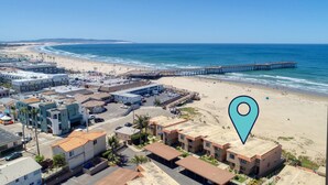 An aerial view of a coastal town with a beach, a pier, and a hotel with multiple buildings and parking. - Classic California Oceanfront Living (Pismo Beach)