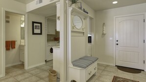 A clean, well-lit entryway with a bench, a door, and a laundry area visible in the background. - Classic California Oceanfront Living (Pismo Beach)