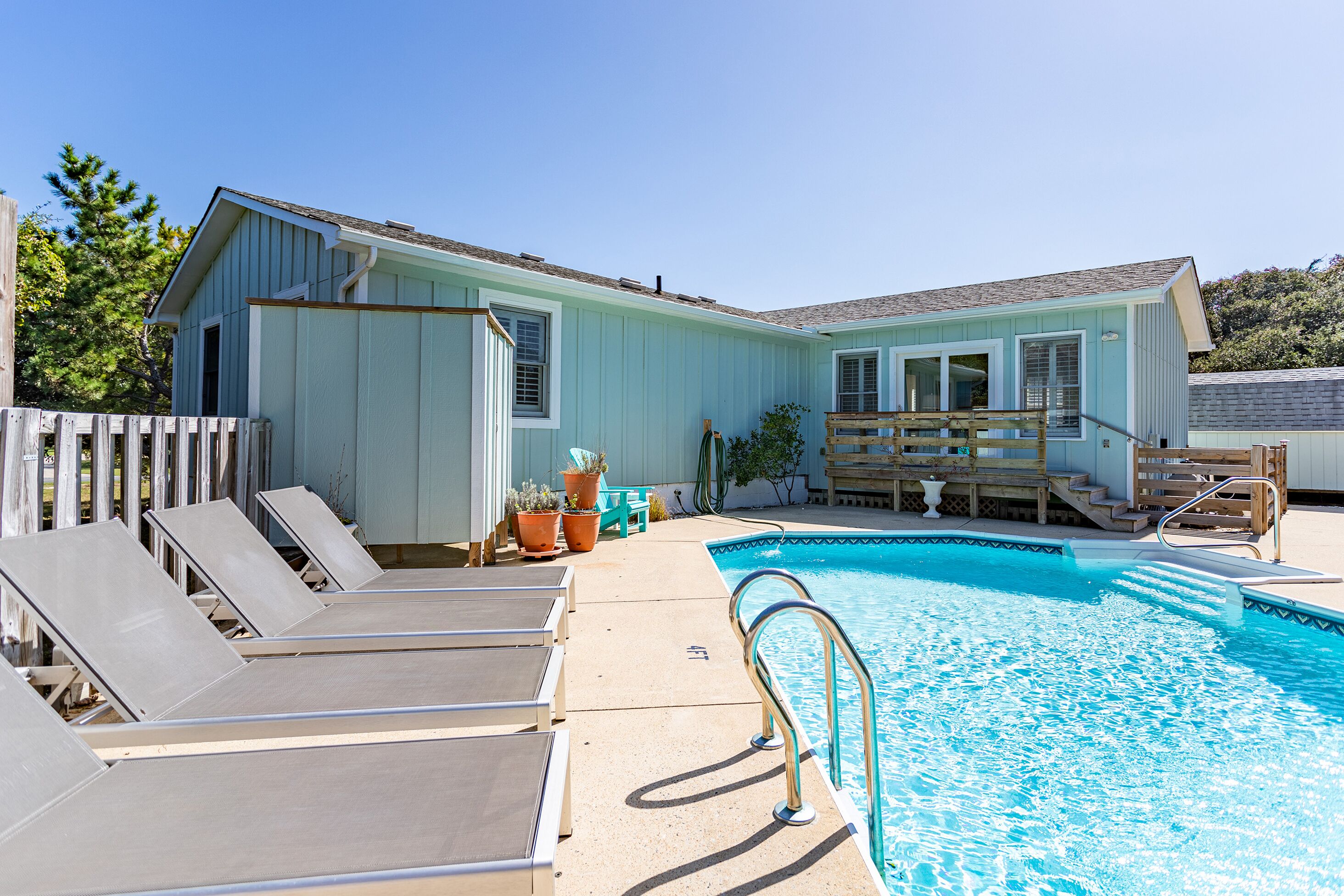 Un espace piscine avec des chaises longues et une terrasse en bois.