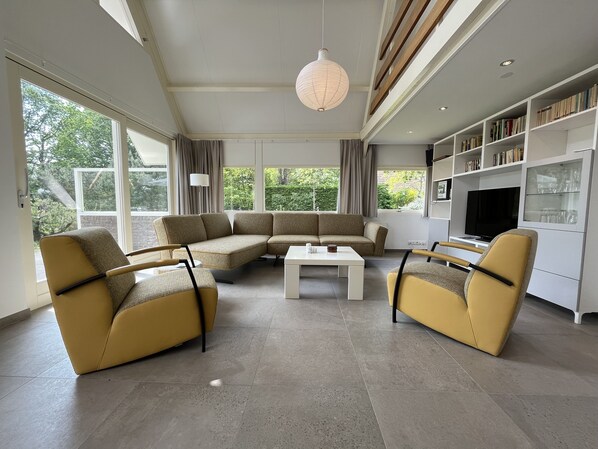 Una sala de estar moderna con un sofá modular, dos sillones, una mesa de centro y un televisor.