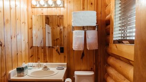 Een betegelde badkamer met een wastafel, spiegel en twee handdoeken die aan een rek hangen.