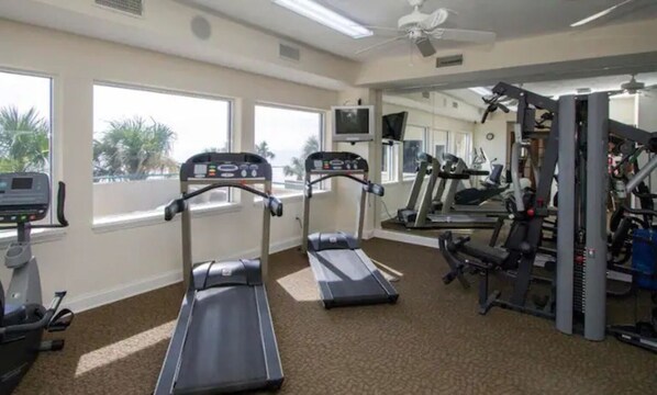 A gym with treadmills, weight machines, and a TV. - STUNNING 3 BED / 3 BATH OCEANFRONT CONDO (Daytona Beach)