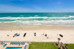 A beach view with a swimming pool and beach chairs. - STUNNING 3 BED / 3 BATH OCEANFRONT CONDO (Daytona Beach)