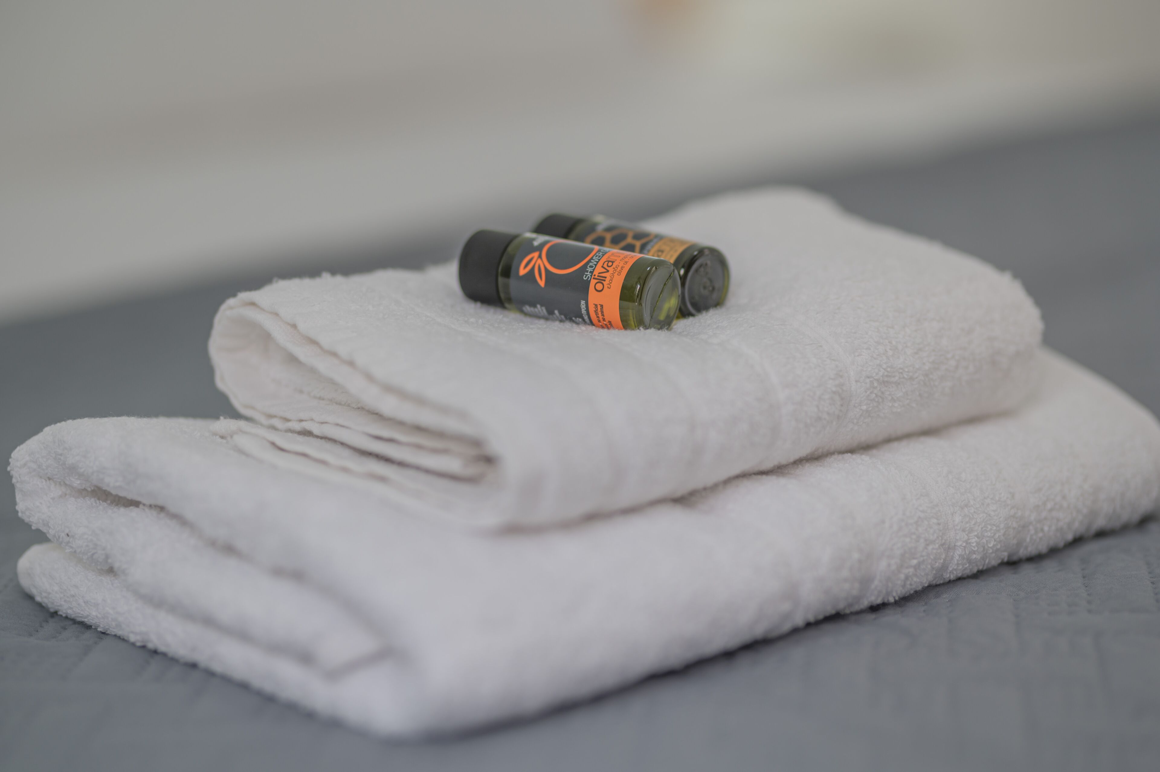 A neatly folded white towel with a bottle of olive oil on top.