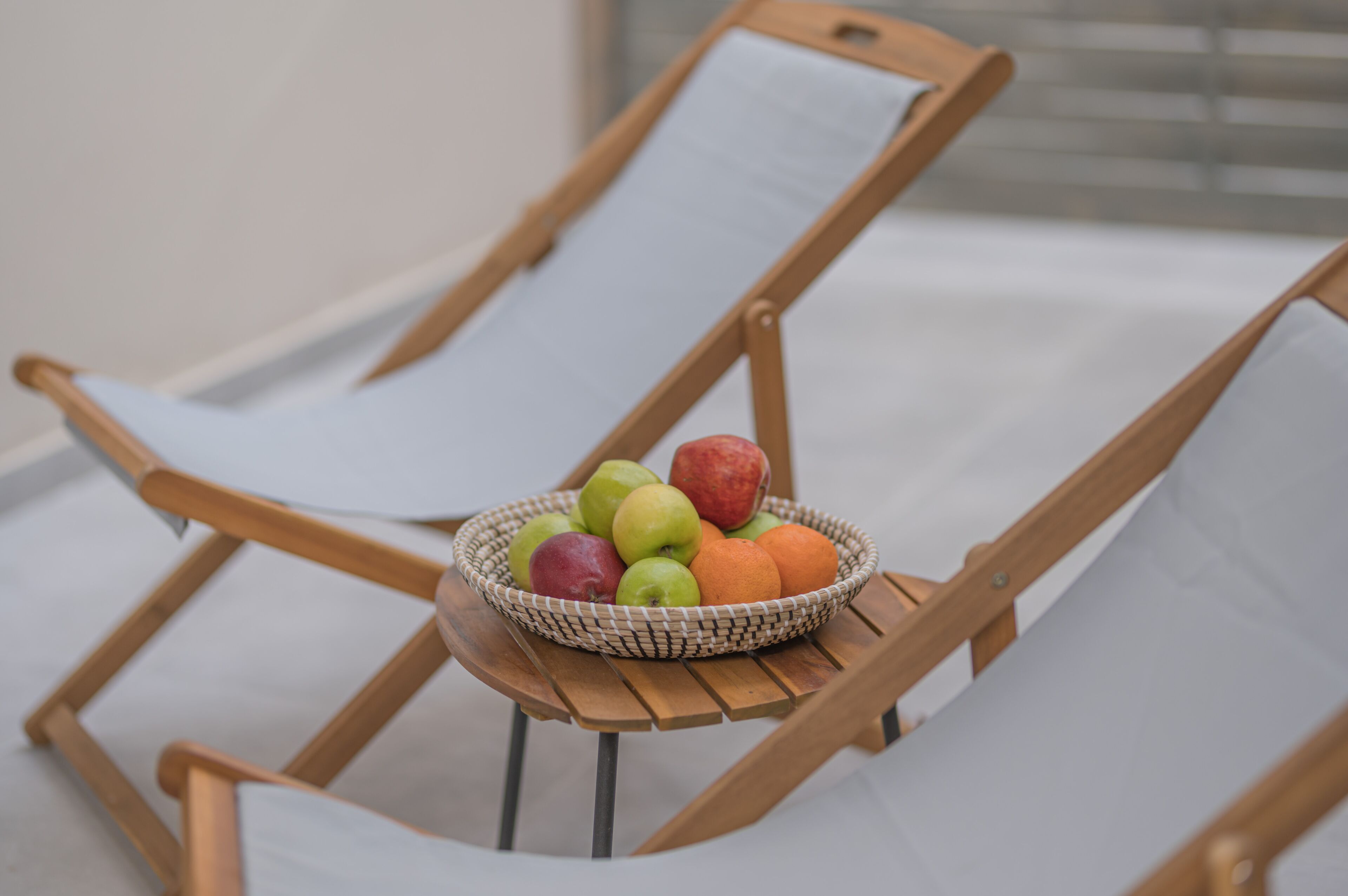 A wicker fruit basket on a wooden chair with a white cushion.