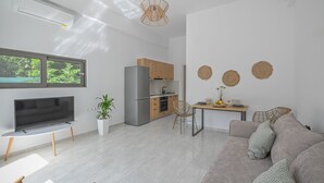 A modern living room with a flat-screen TV, a sofa, and a dining area with a table and chairs. - Moka Apartments (Chania)