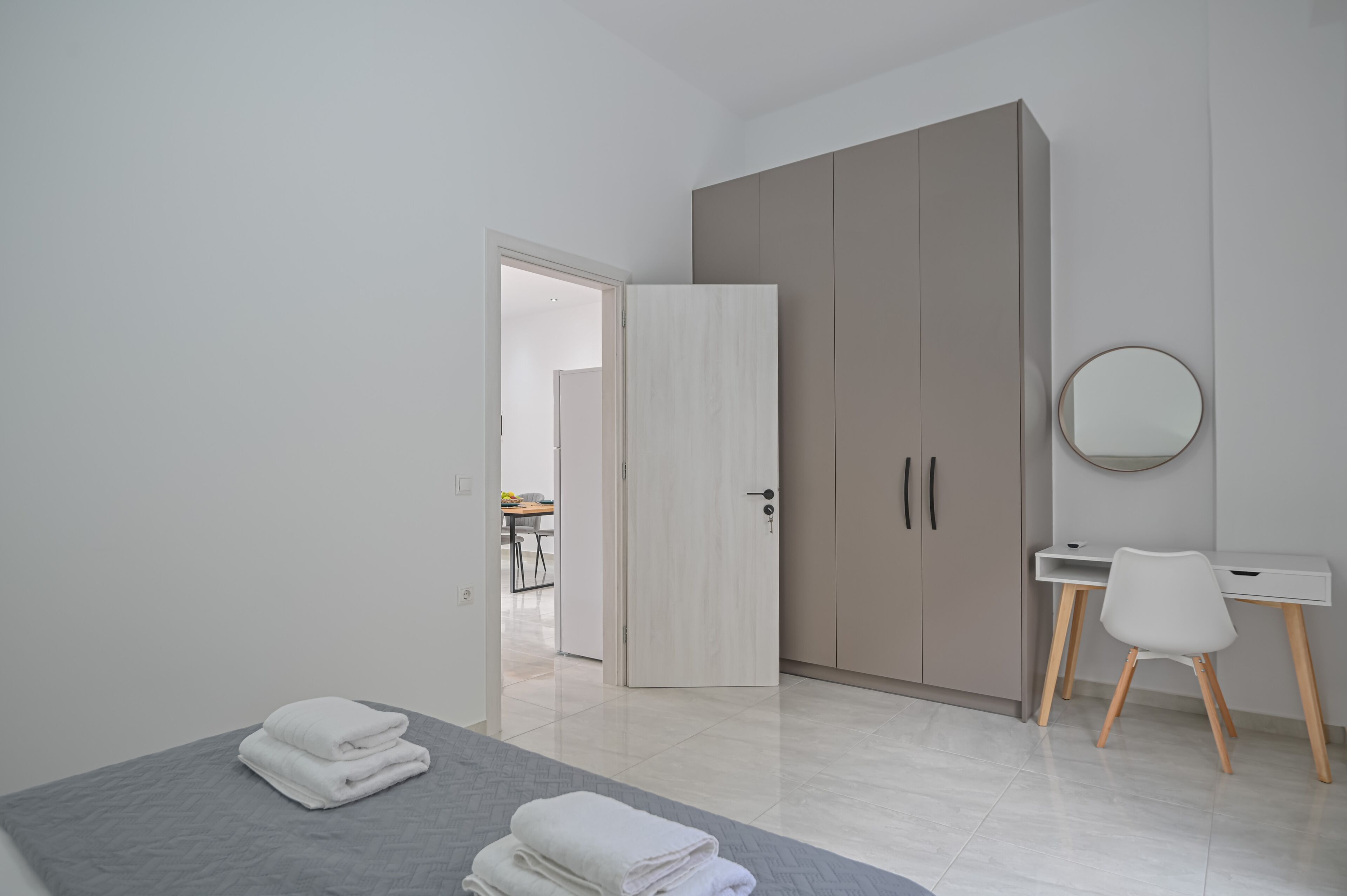 A modern bedroom with a bed, a desk, and a wardrobe.