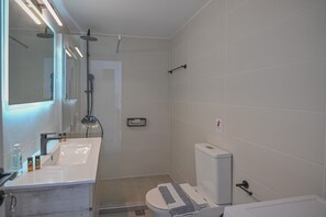 Un baño moderno con lavamanos, espejo y retrete blancos.