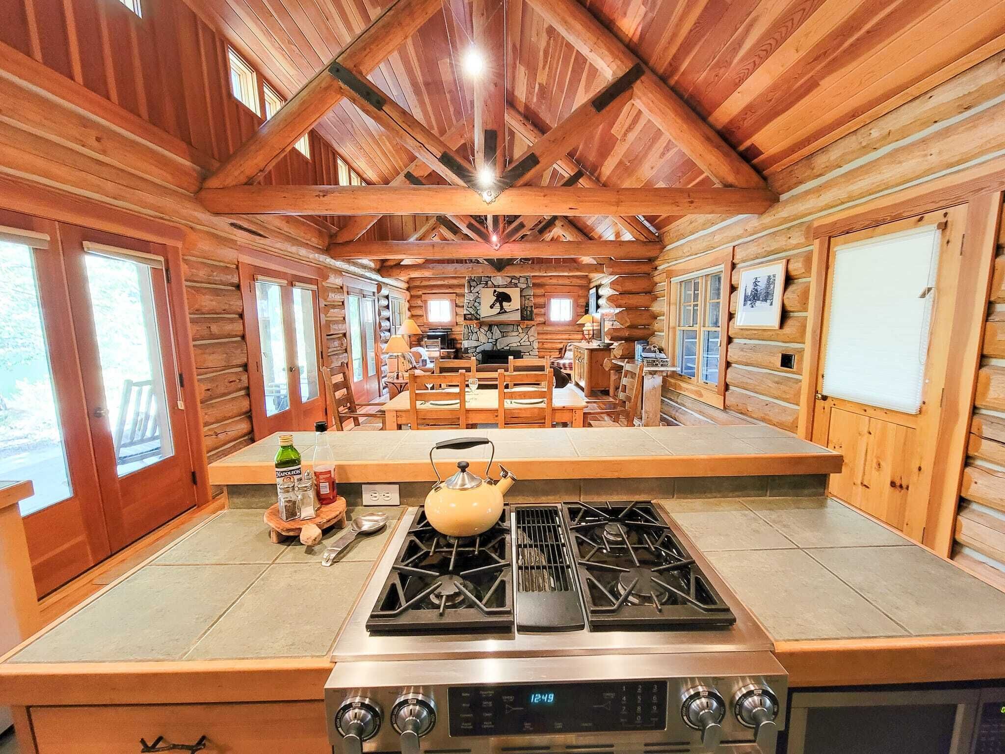L’intérieur d’une cabane en rondins comprend un espace cuisine équipé d’un poêle, d’une table à manger et de chaises.