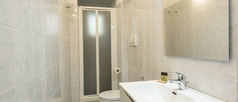Un bagno con doccia, WC e lavandino.
