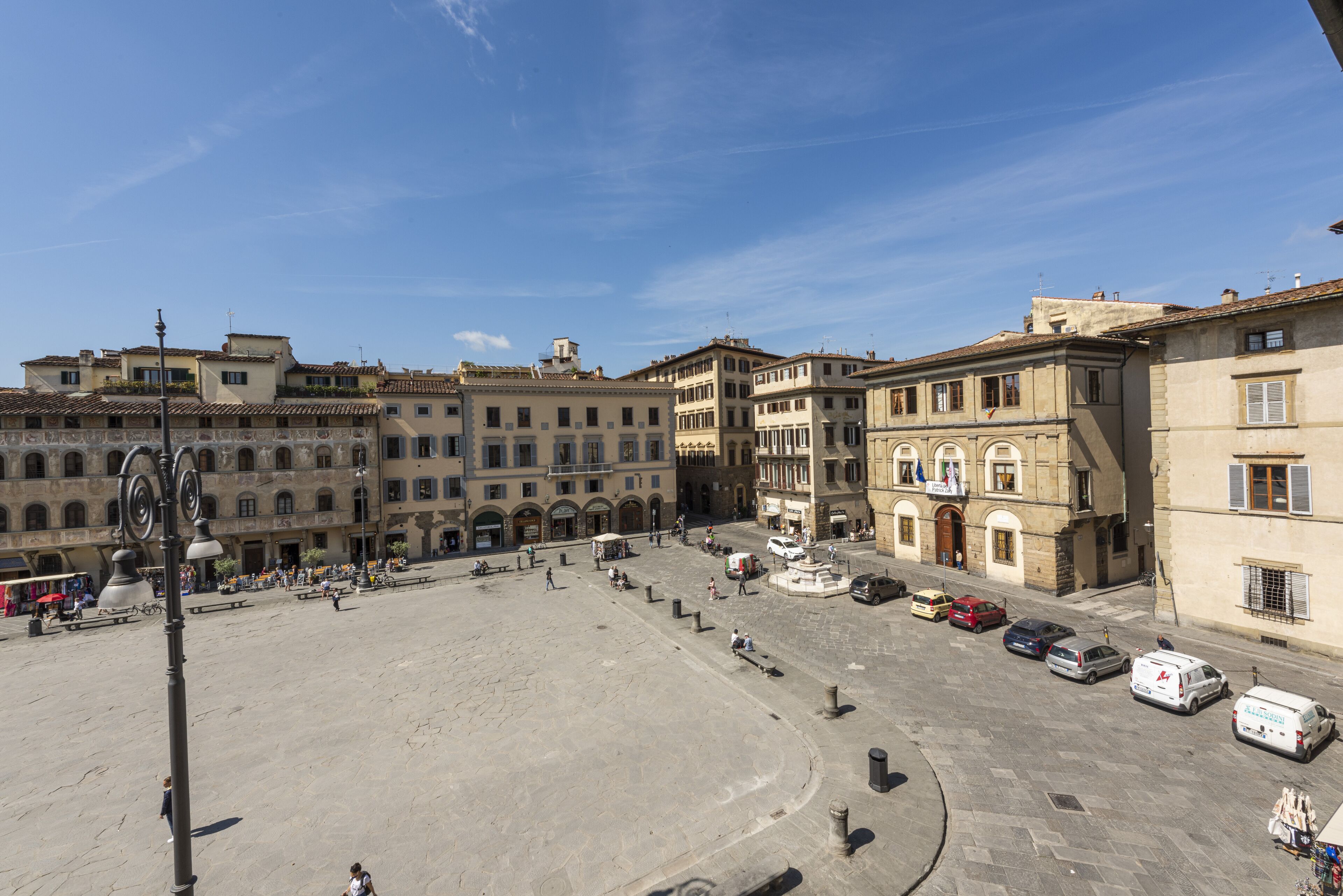A spacious public square with historic buildings, a central fountain, and a clear sky.