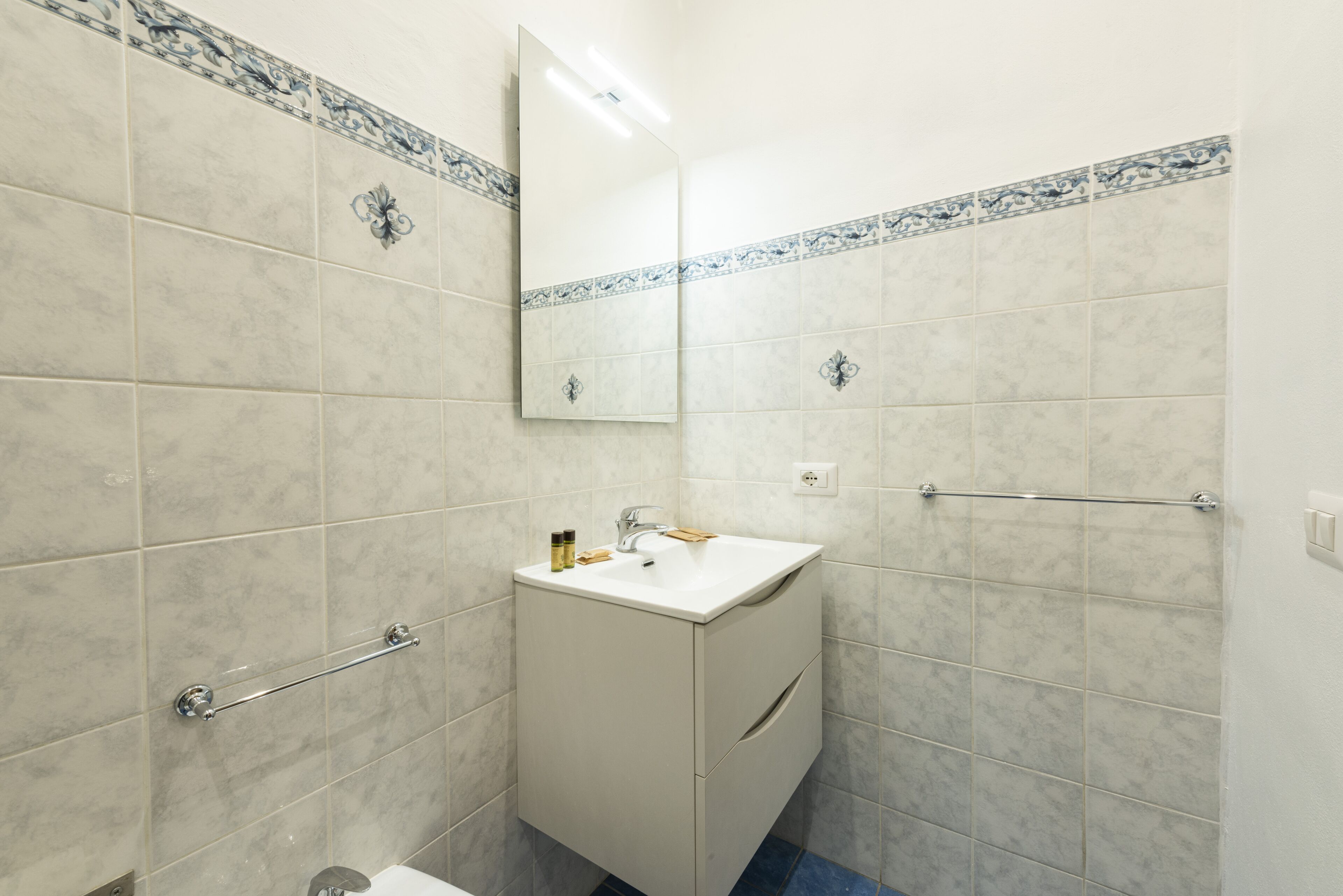Ein Badezimmer mit Waschbecken, Spiegel und Fliesen.