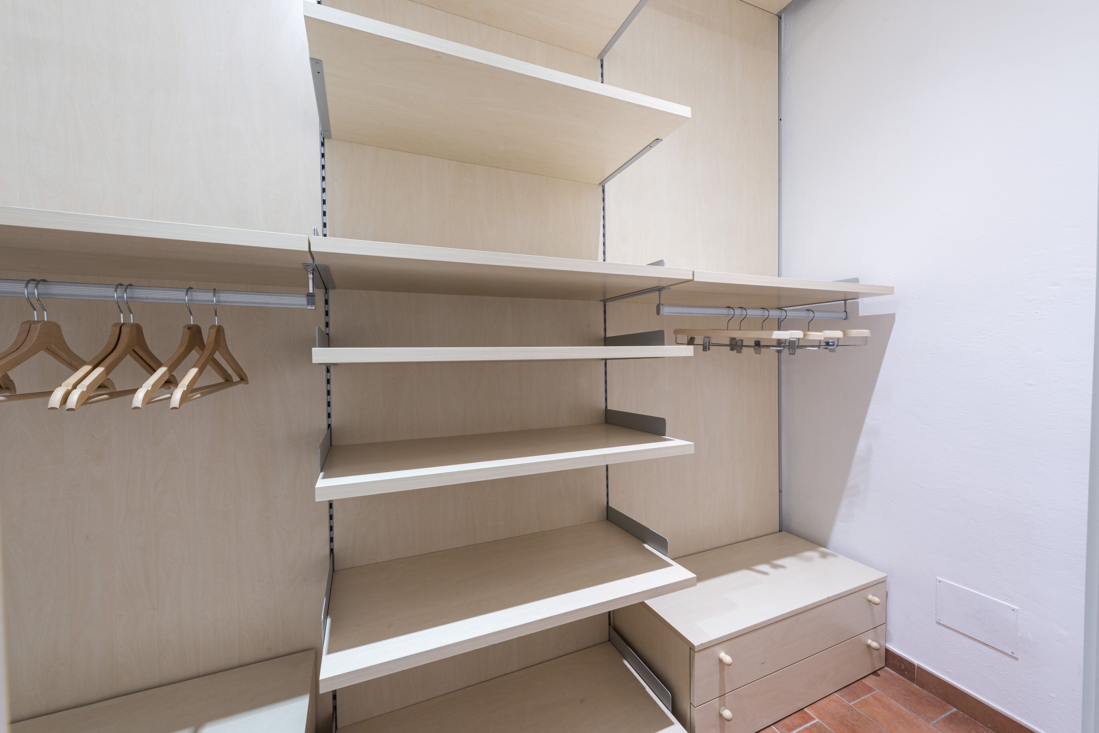 A modern closet with multiple shelves and hanging space.