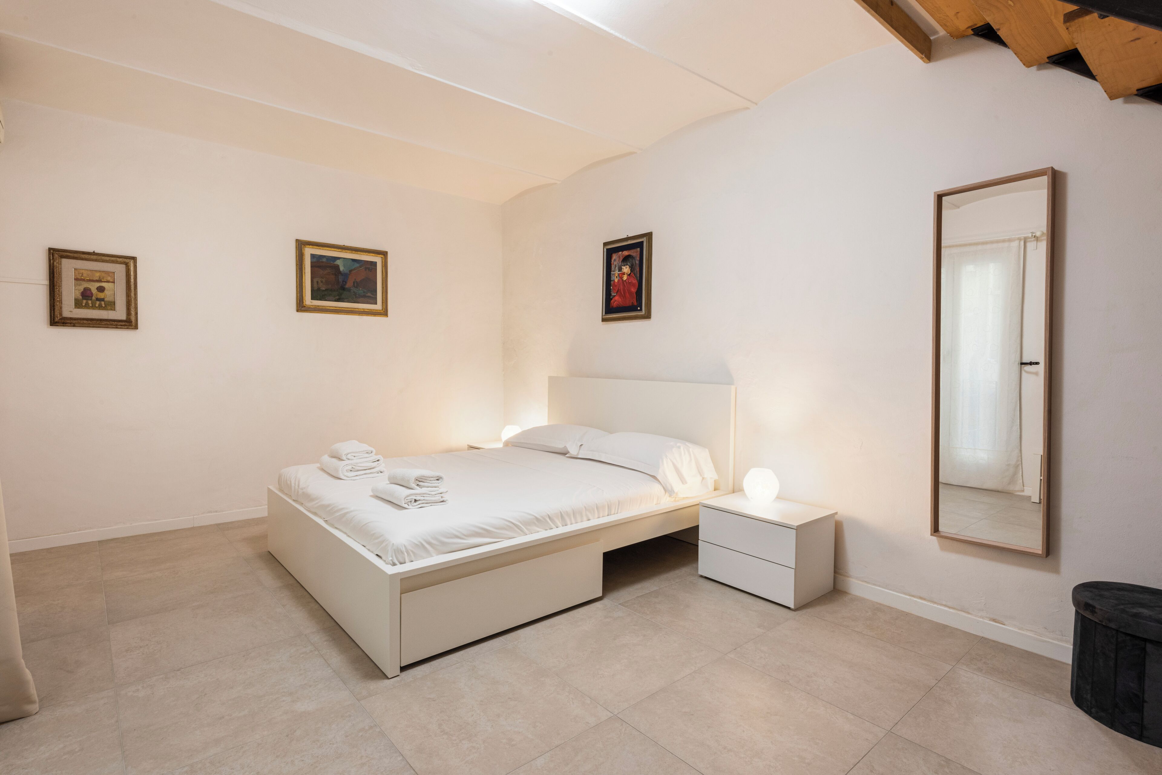 A bedroom with a single bed, bedside tables, and a large mirror.
