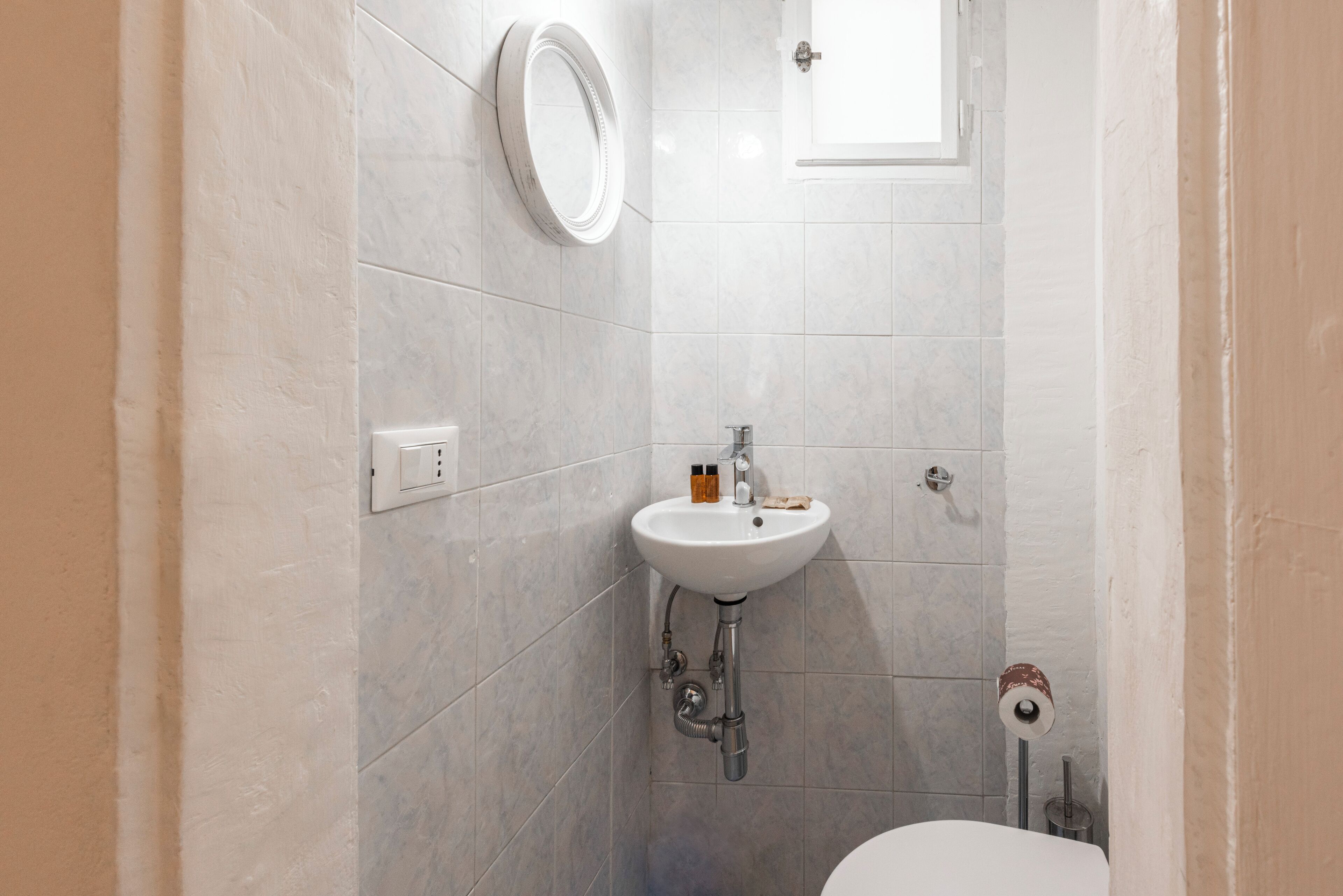 A bathroom with a white sink, a mirror, and a toilet.