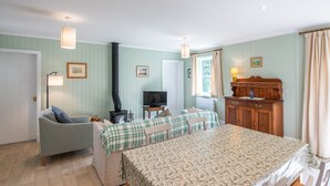 Een gezellige kamer met een bed, twee stoelen, een bank, een televisie, een houten kast en een open haard.