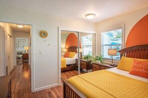 A bedroom with a bed, bedside table, lamp, and a mirror.