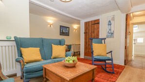 A cozy living room with a blue sofa, a wooden coffee table, and a blue rocking chair. - Bell Cottage (Dorchester)