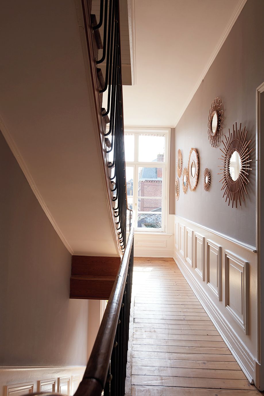 Eine Treppe mit einer Holzhandläufe und einem Ausblick nach draußen durch ein Fenster.