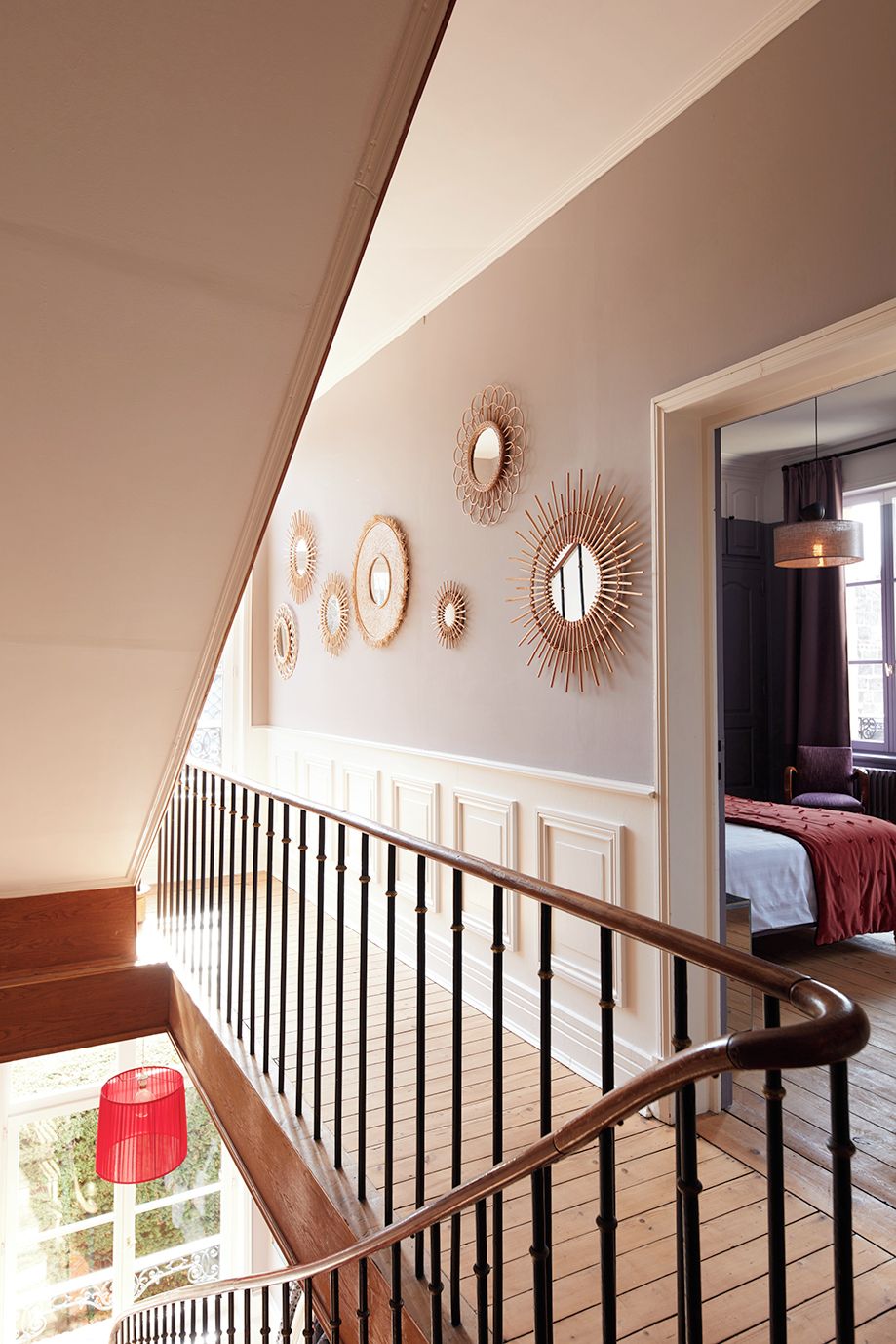A staircase with a wooden handrail leading to a room with a bed and a window.