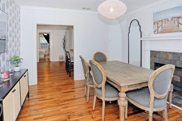Un comedor con mesa y sillas de madera, una chimenea y un pasillo que conduce a otra habitación.