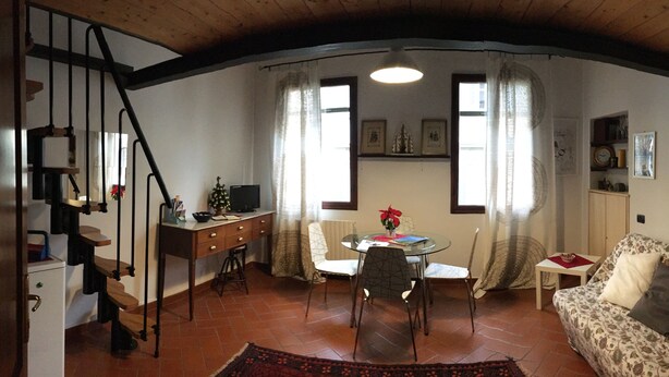A cozy living room with a staircase, a dining area, and a sofa. - Sofia's Nest (Firenze)