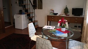 A living room with a glass table, two chairs, a small Christmas tree, a television, and a staircase. - Sofia's Nest (Firenze)