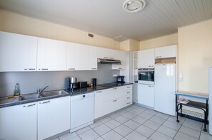 A modern kitchen with white cabinets, a stainless steel sink, a dishwasher, a coffee maker, and a microwave.