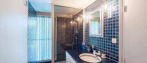 A bathroom with a shower, a sink, and a mirror.