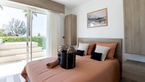 A bedroom with a bed, a large window, a framed picture, and a wooden headboard. - Le Palm Beach - Jacuzzi et vue mer (Sanary-sur-Mer)