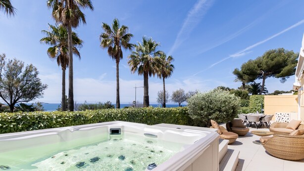 A hot tub with clear water, surrounded by outdoor furniture and palm trees. - Le Palm Beach - Jacuzzi et vue mer (Sanary-sur-Mer)