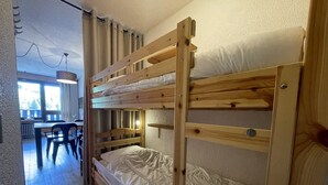 Ein Schlafzimmer mit Etagenbetten, einem Holzkopfteil, einem Schreibtisch und einem Stuhl.