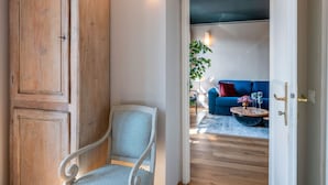 A room with a wooden door, a blue sofa, and a coffee table with decorative items. - Genteel Home Piazza Pitti I (Florence)