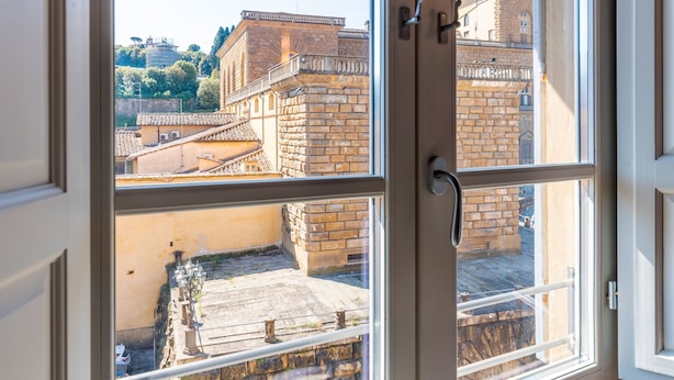 A view through a window of a building with stone walls and a balcony. - Genteel Home Piazza Pitti I (Florence)