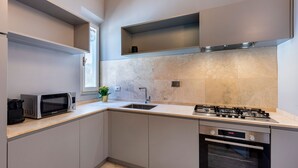 A modern kitchen with a built-in microwave, gas stove, oven, and a sink. - Genteel Home Piazza Pitti II (Florence)